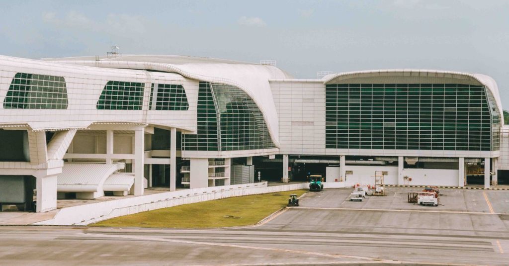 Bâtiment blanc d’un terminal d’aéroport vu depuis le tarmac