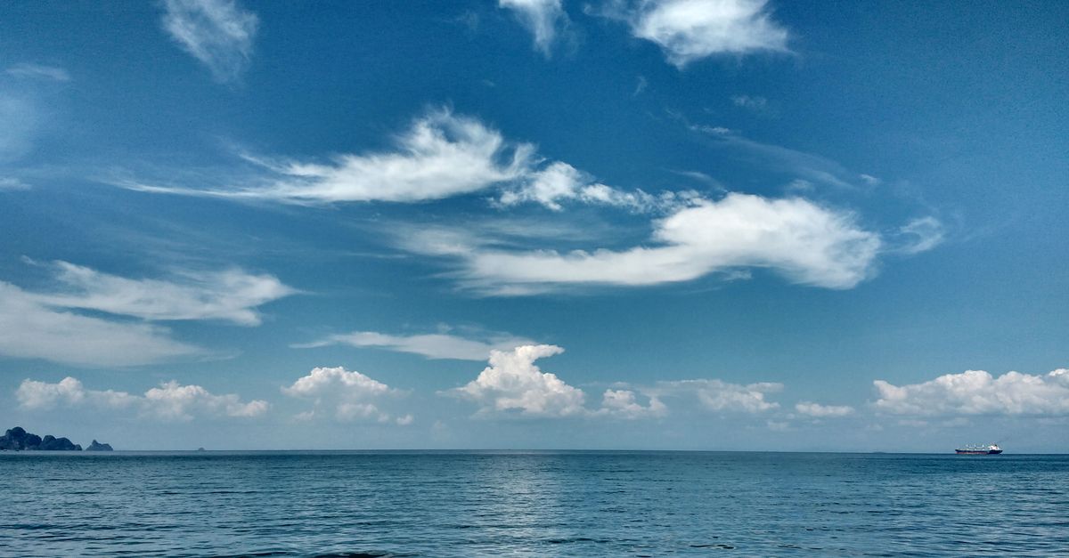Mer calme sous un ciel bleu parsemé de nuages