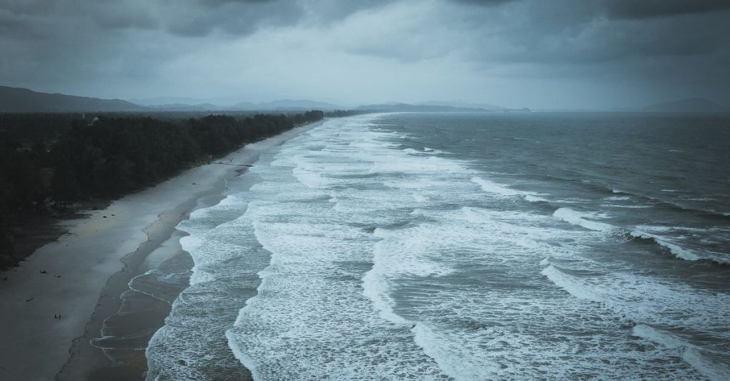 Vagues sur une plage sous un ciel sombre et nuageux