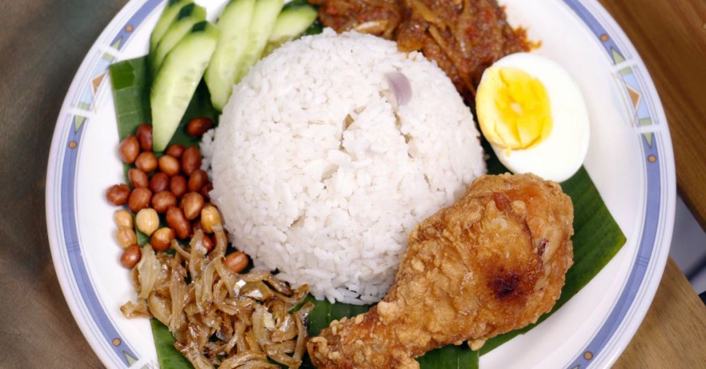 découvrez le nasi lemak, plat emblématique de malaisie : un riz parfumé au lait de coco, accompagné de sambal, d’œuf, d’anchois et de cacahuètes.