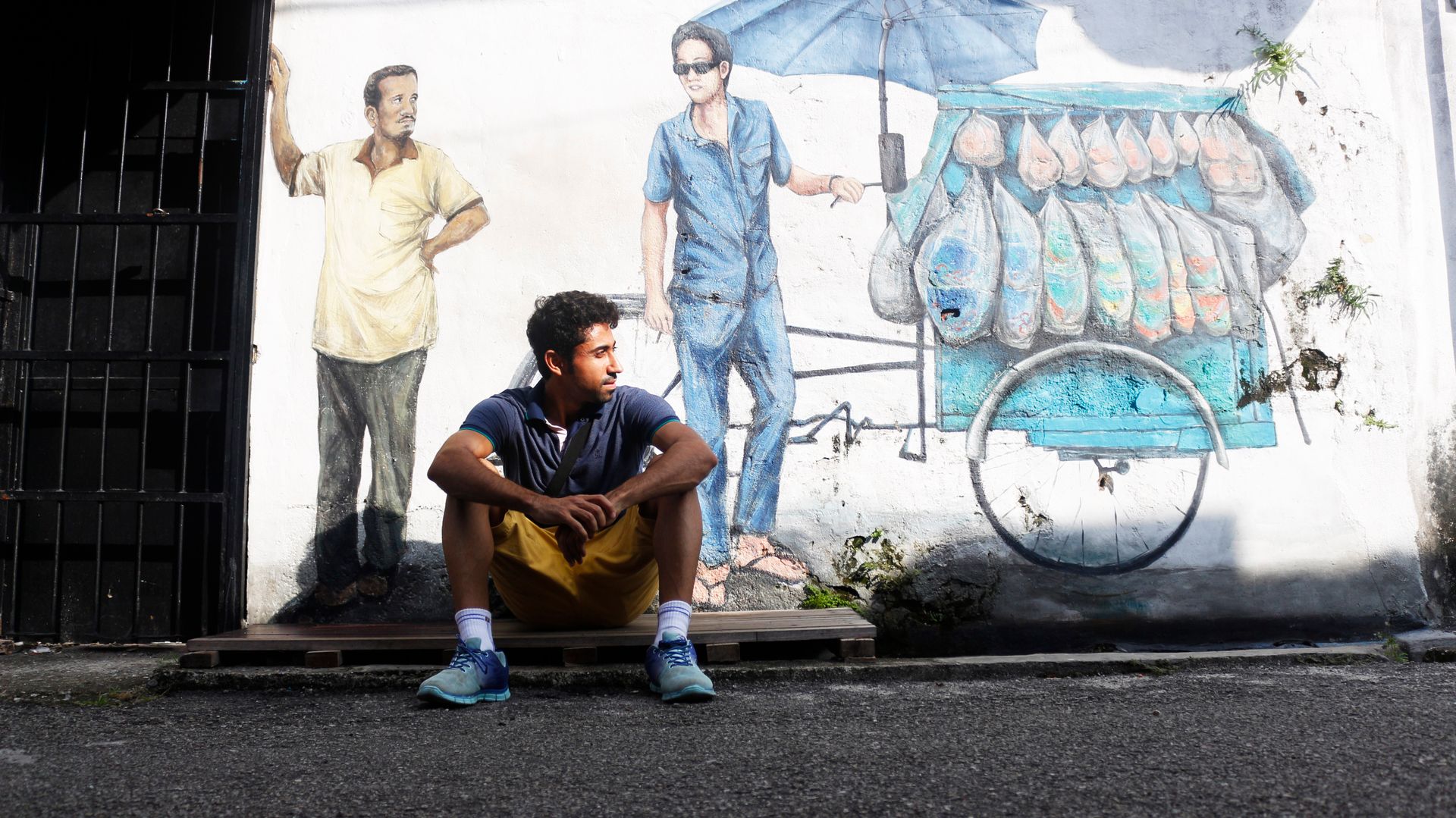 Street art coloré représentant un enfant sur un vélo à George Town, Penang, avec des bâtiments coloniaux en arrière-plan